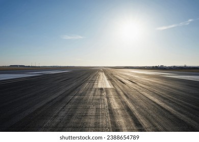 Surface level of long airport runway with directional marking against clear sky.  - Shutterstock ID 2388654789