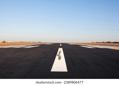 Surface level of long airport runway with directional marking against clear sky.  - Shutterstock ID 2389806477