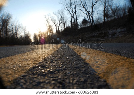 Surface level shot of a sunset over the center line of a rural highway.
