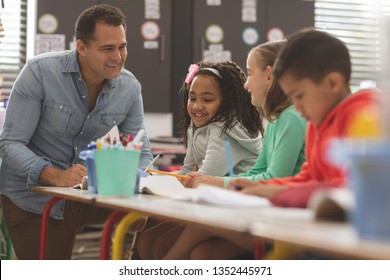 Surface level view of a teacher interacting with school kids while sitting in classroom 