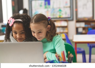 Surface Level View Of Two Schoolgirl Having A Smirk While They Working On Their Laptop In Classroom At School