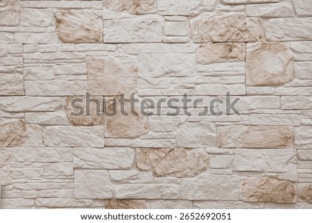 A surface of light-colored, textured stone blocks is arranged orderly, highlighting natural variations in tone and detail, creating a warm and inviting atmosphere.