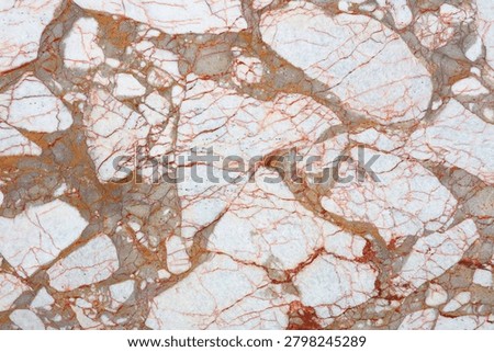 A surface of natural stone with various patterns. The stone features a light background with dark and orange veins. It appears smooth and polished.