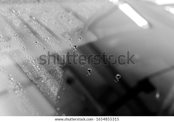The Surface\
Protection of the car windows at the car wash under the jets of\
water. Black and white\
photo