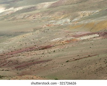 The surface of steppe in different shades, texture. Sightseeing area in Altai mountains. Cloudy and windy weather, summer. Hills around.