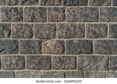 The Surface Texture Of The Black Granite Brick Wal With Grey Concrete In The Gaps.