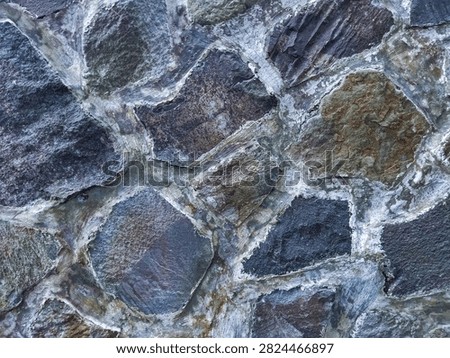 The surface texture of a natural stone wall or rubble stone masonry arranged irregularly and bonded with mortar or cement.