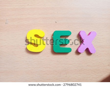 The surface texture of the table is marked with the word SEX using colorful wooden toy blocks. selective focus 