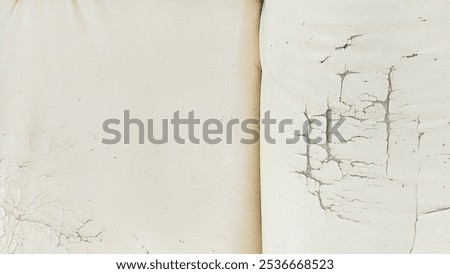 The surface of the white leather sofa has cracks and peeling, revealing the underlying fabric and giving an aged, distressed appearance.

