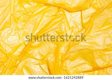 Surface of yellow wrinkled plastic bag. Texture of plastic film. Coating of polyethylene membrane. Abstract crumpled background.