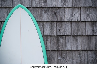 A Surfboard Leans Against A Cedar Shingle Wall.