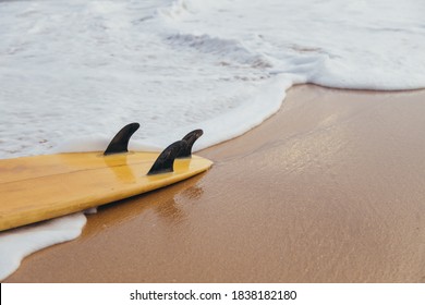 Surfboard Lying On The Sand Beach In The Foam Of The Ocean Waves.