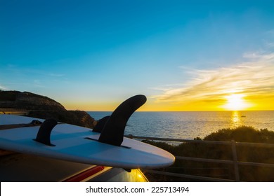 Surfboard On A Car Rooftop At Sunset