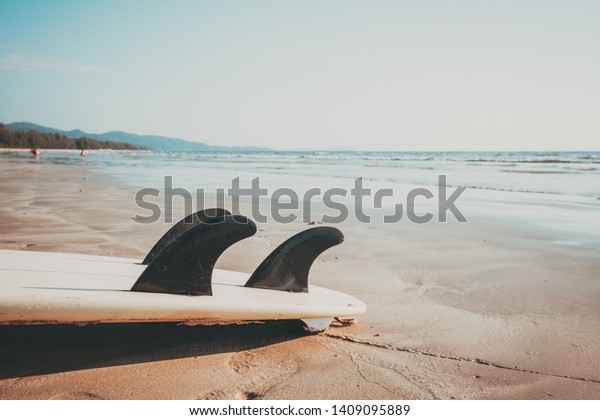 Surfboard on sand tropical beach with\
seascape calm sea and sky background. summer vacation background\
and water sport concept. vintage color tone\
effect.