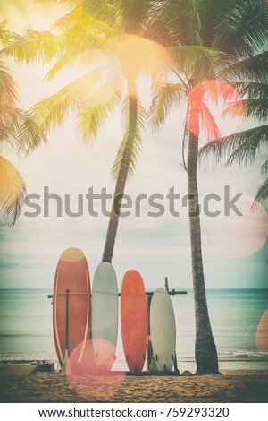 Surfboard and palm tree on beach double exposure with colorful bokeh sun light texture abstract background. Summer vacation and sport extreme concept. Vintage tone filter color style.