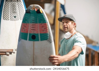 Surfboard shaper workshop- surfshop employee admiring surfboard - Powered by Shutterstock