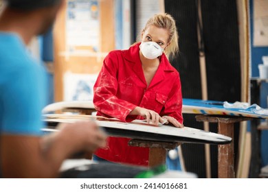 Surfboard shaper workshop- surfshop employee working on surfboard - Powered by Shutterstock