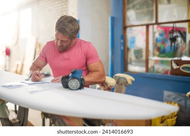 Surfboard shaper workshop- surfshop employee filling out paper work - Powered by Shutterstock