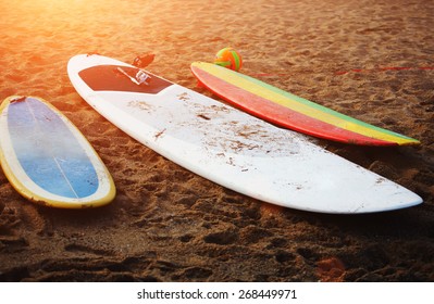 Surfboards lying on the beach at sunny flare light evening in summer, colorful surfboard on the sand, summer time with best friends - Powered by Shutterstock