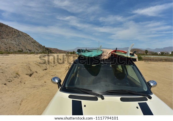 surfboards on\
roof of car at beach in Baja,\
Mexico