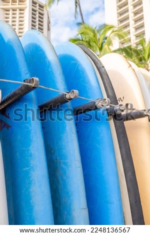 Surfboards on Waikiki Beach standing in a rack at a beach rental shop.