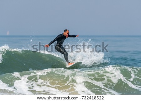 Surfer in action with a small action camera on the ocean waves on a sunny day.