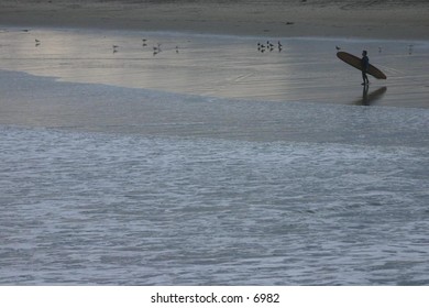 surfer approaching the ocean with board under arm