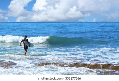 Surfer In Black Wet Suit Walking In To Water On Sunny Day