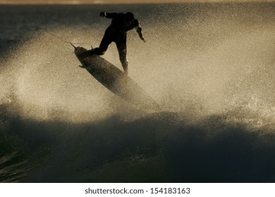 A surfer flies above a wave at sunrise. - Shutterstock ID 154183163