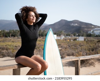 Surfer girl with afro hair sitting on a fence - Powered by Shutterstock