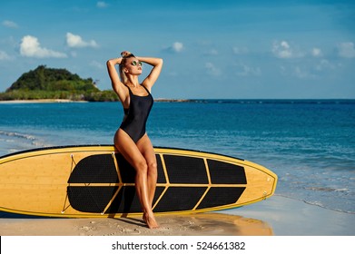 Surfer girl in bikini and sunglasses enjoying freedom on the beach