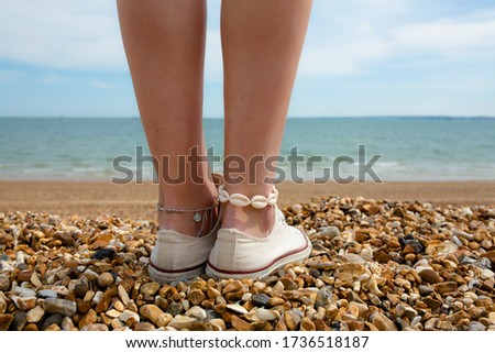 Surfer girl on shingle beach with shell anklet
