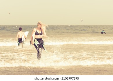 Surfer Girl Running With Surf Boards On The Beach. Sporty People Having Fun In Surfing Day. Extreme Sport, Travel And Holiday Concept.