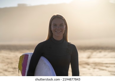 Surfer girl smiling at the beach with her surfboard at sunrise morning light. Female surfer woman - Powered by Shutterstock