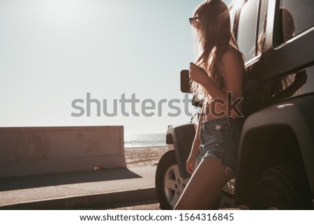 surfer girl standing by a car at the beach. california