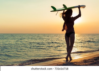 Surfer girl surfing looking at ocean beach sunset