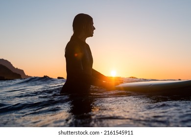 Surfer girl waiting for a wave in the water at sunset - Powered by Shutterstock