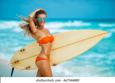 Surfer girl walking with board on the sandy beach. Surfer girl. Beautiful young woman at the beach. water sports. Healthy Active Lifestyle. Surfing. Summer Vacation. Extreme Sport. 