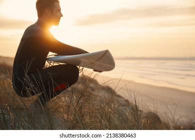 A surfer with his surfboard at the dunes looking to the waves - Powered by Shutterstock