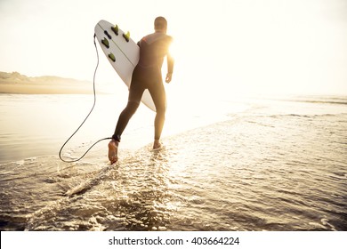 A surfer with his surfboard running to the waves - Powered by Shutterstock