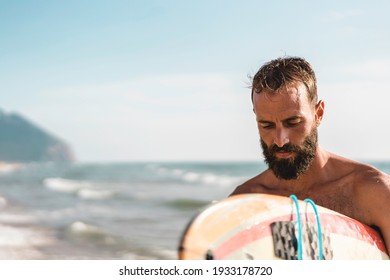 Surfer holding his surfboard walking on the beach - Hipster man training with surfboard - Lifestyle and freedom concept - Powered by Shutterstock