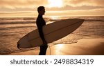 A surfer holding a surfboard while standing on the beach at sunset. The scene evokes feelings of adventure and serenity.