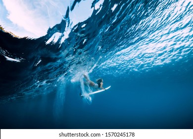 Surfer make duck dive underwater. Surfgirl dive under big wave