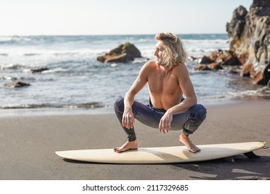 Surfer Man Standing On Surfboard On The Beach - Extreme Sport Concept