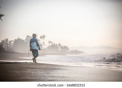 Surfer on a beach headed towards the ocean.
