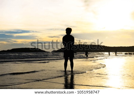 Surfer on the ocean beach at sunset on Koh Chang, Thailand