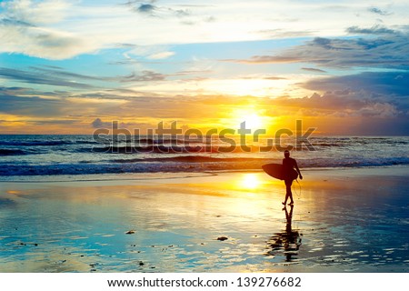 Surfer on the ocean beach at sunset on Bali island, Indonesia