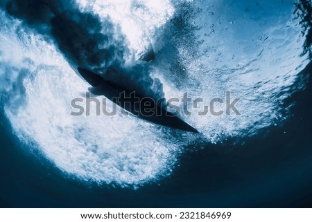 Surfer on surfboard in ocean underwater view. Crashing wave and surfboard