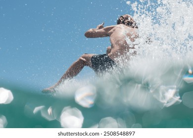 A surfer passes by, creating a dynamic scene with water droplets suspended in the air, capturing the thrill of riding the waves and the vibrant energy of a day spent surfing in the ocean.