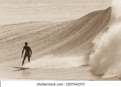 Surfer Rear View Surfing Ride On Ocean Wave In Sepia Vintage Tone.